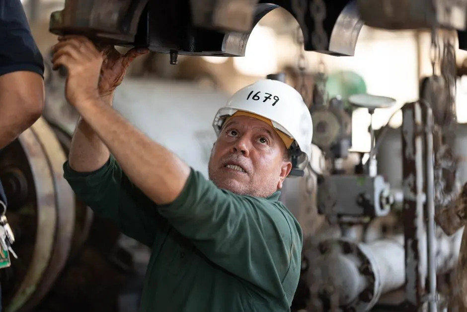 Engineer examines heavy machinery in an industrial site, showcasing technical expertise.